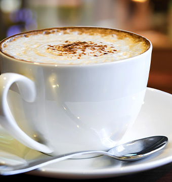 A perfect cup of coffee served on a plate with mixing spoon